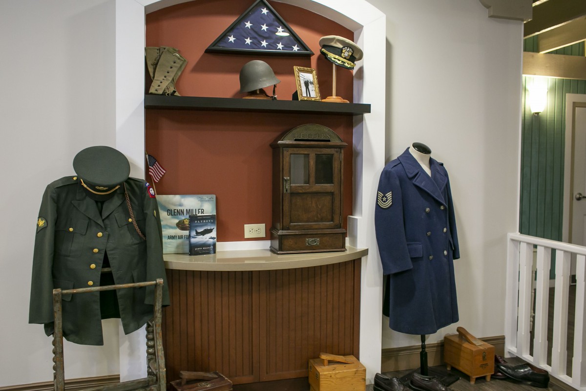 A museum display featuring military uniforms, memorabilia, and an American flag.