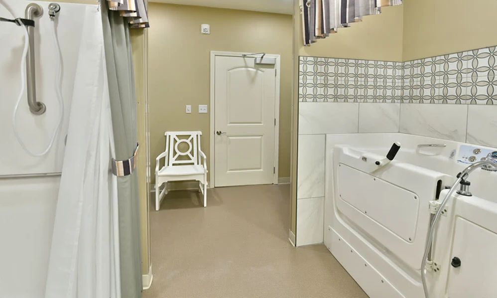 A bathroom interior featuring a bathtub, a white chair, and a door with curtains on the window.