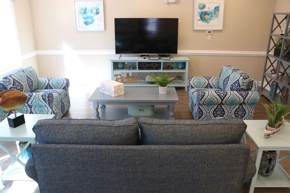 A cozy living room setup featuring a TV, sofa, coffee table, and patterned armchairs with decorative elements.