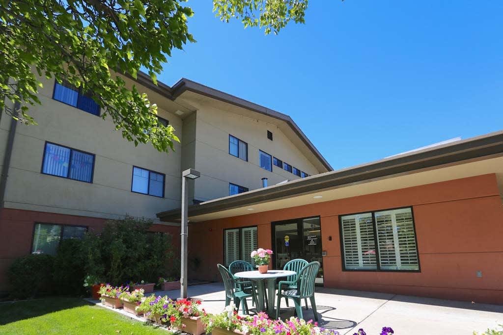 A sunny day at a residential building with a garden patio and outdoor seating.
