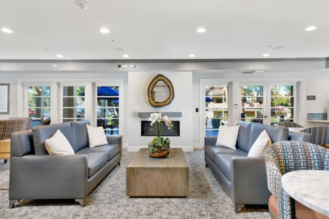 A modern living room with two gray sofas, a central coffee table, and a fireplace adorned with a decorative mirror.