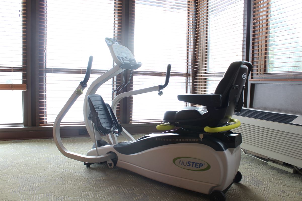 A recumbent elliptical machine positioned in a well-lit room.