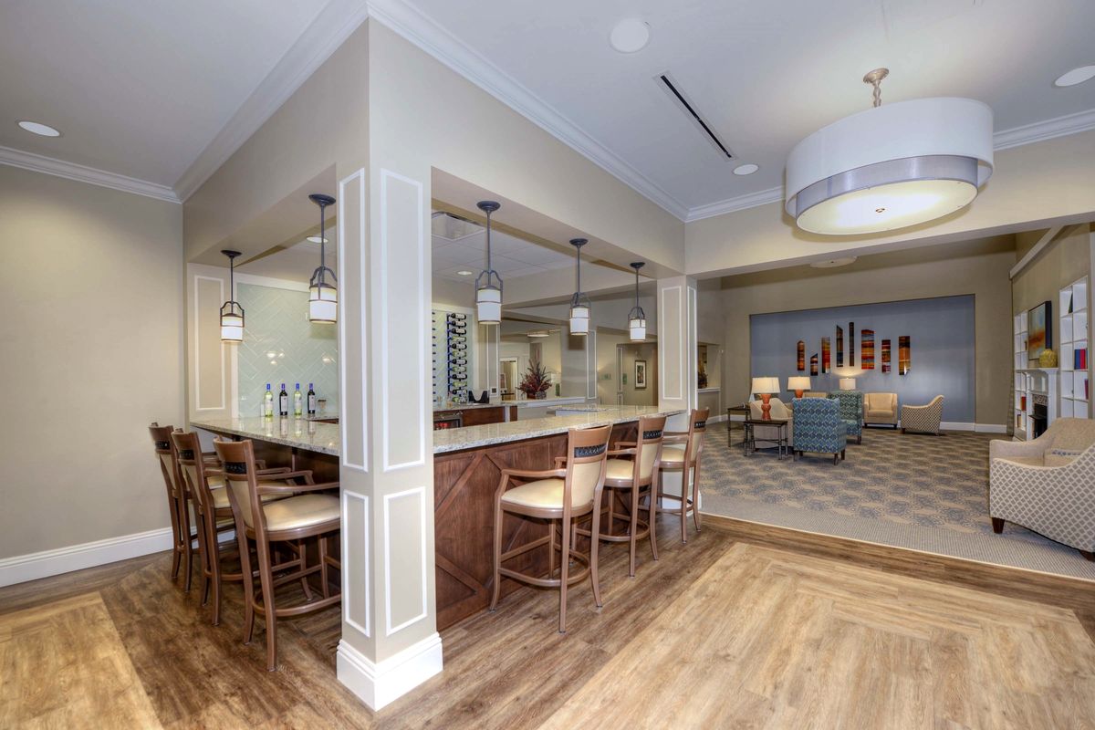 A modern kitchen with a bar area featuring seating and pendant lighting, showcasing contemporary design elements and wood flooring.