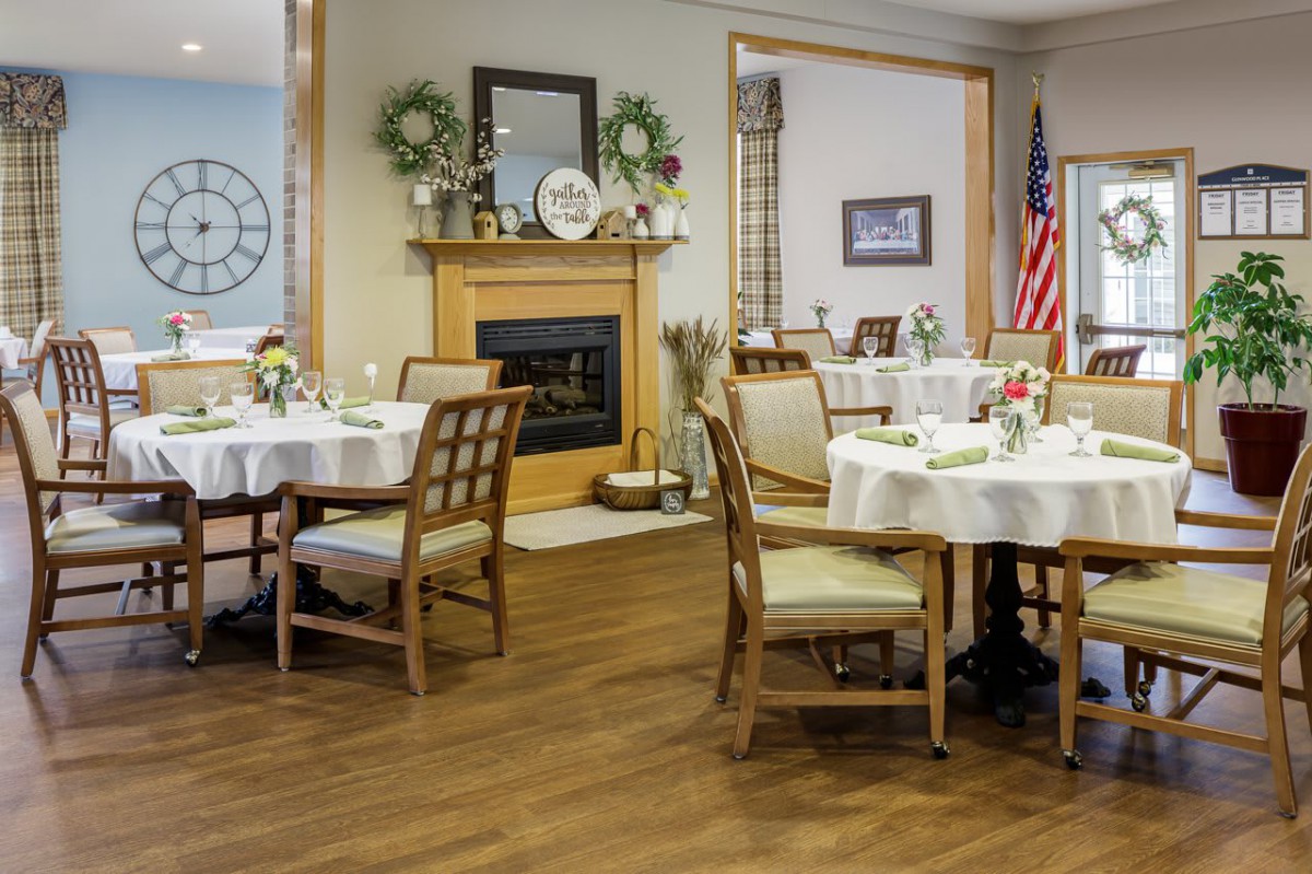 A well-decorated dining area with tables and chairs, featuring a fireplace and an American flag.