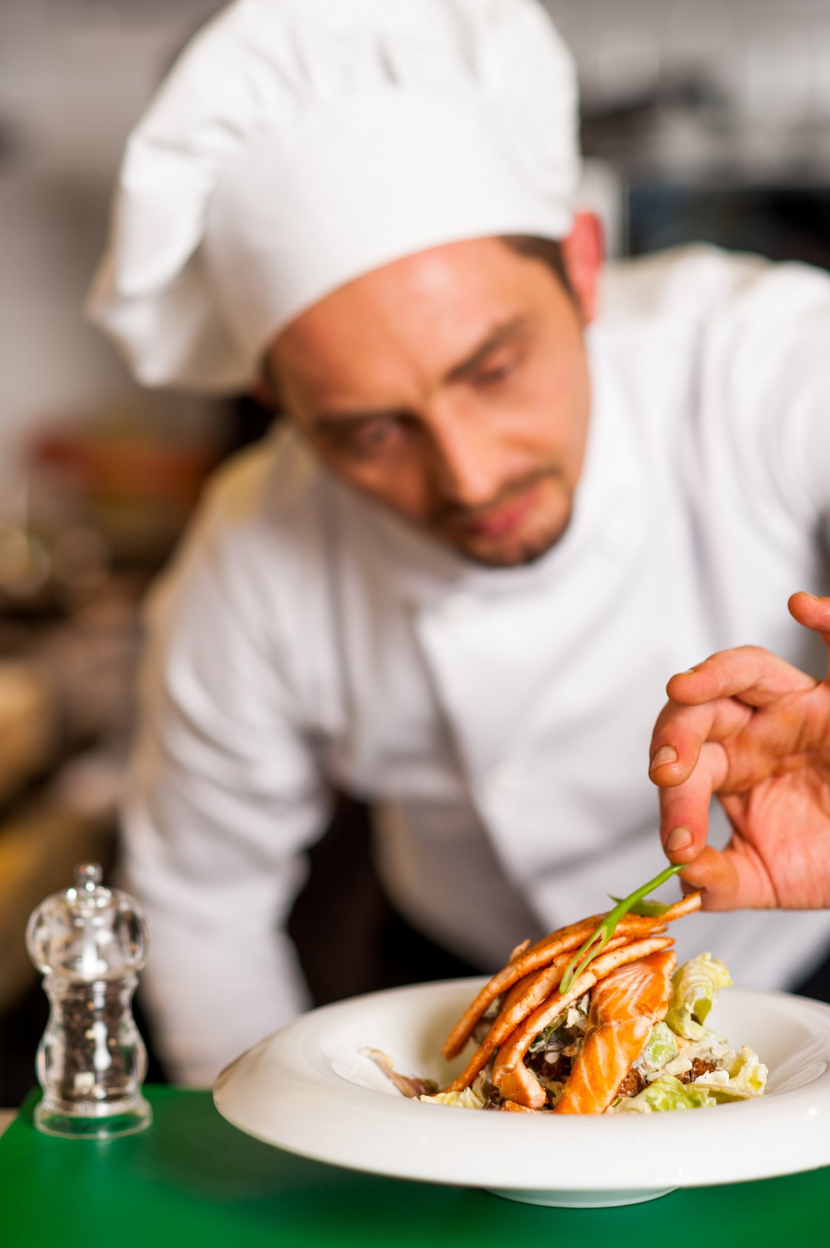 A chef carefully garnishes a gourmet dish in a professional kitchen.