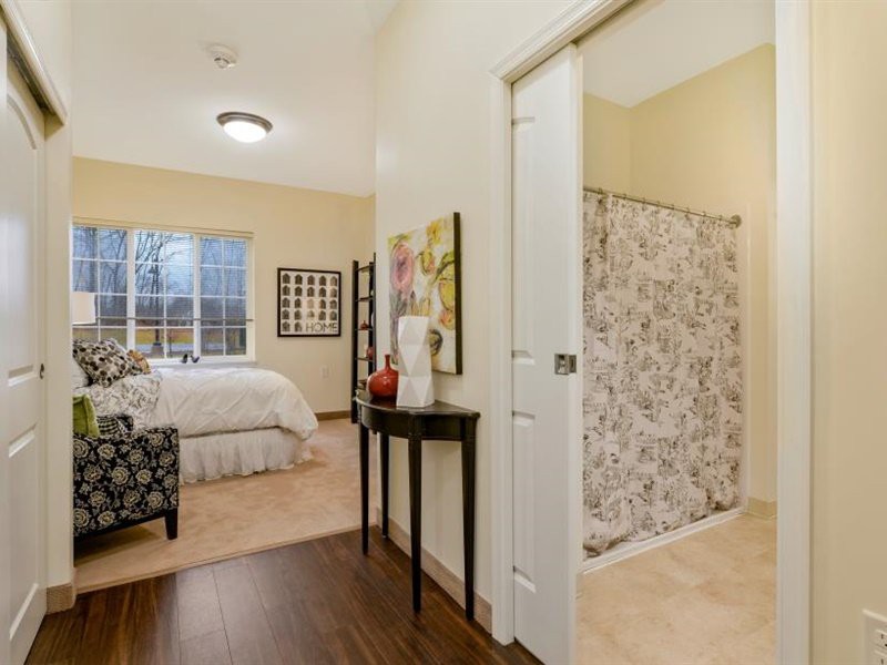 A cozy bedroom with elegant decor, featuring artwork and a soft carpet.