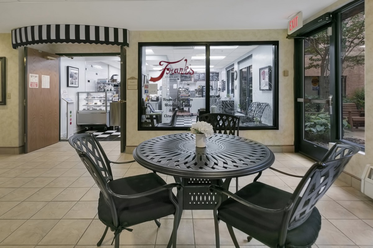 A cozy cafe interior with a round table and chairs, situated near a window showcasing the kitchen area.