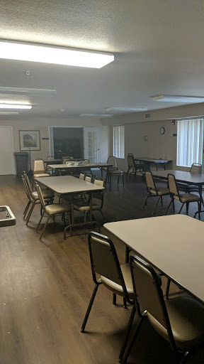 A spacious and empty multi-purpose room with tables and chairs arranged for a gathering.
