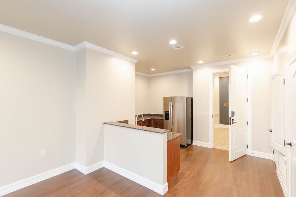 A modern apartment kitchen with wood flooring and recessed lighting.