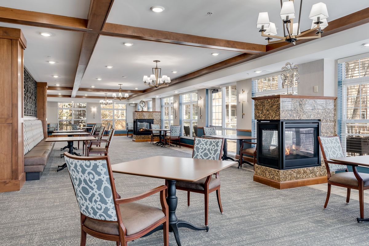 A modern dining area with elegant tables, chairs, and a central fireplace.