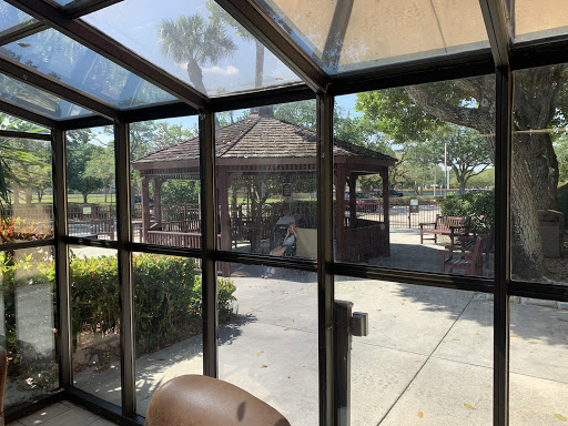 A view from inside a sunlit enclosure overlooking a gazebo and landscaped area.