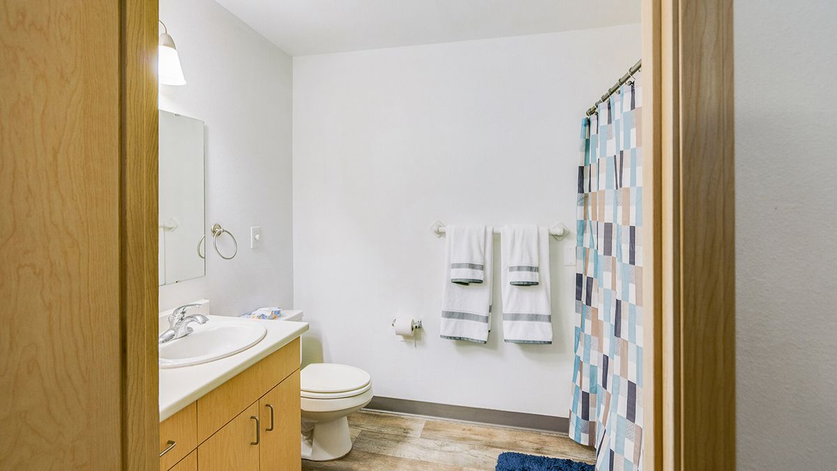 A clean and bright bathroom with a sink, toilet, and patterned shower curtain.