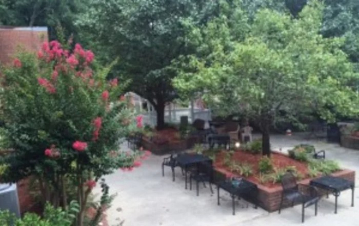 A tranquil garden setting with benches, lush trees, and colorful flowers lining a pathway.