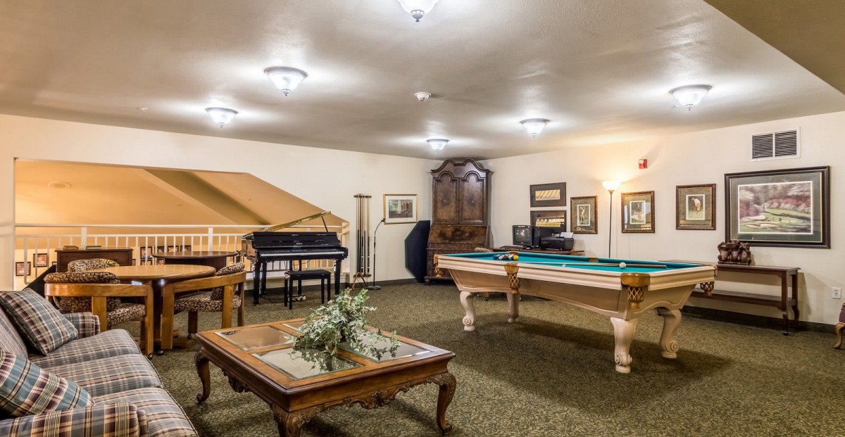A cozy game room featuring a pool table, piano, and elegant furnishings.