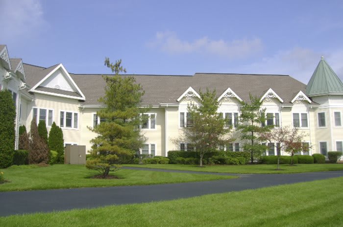 A suburban residential building with a well-maintained lawn and trees.