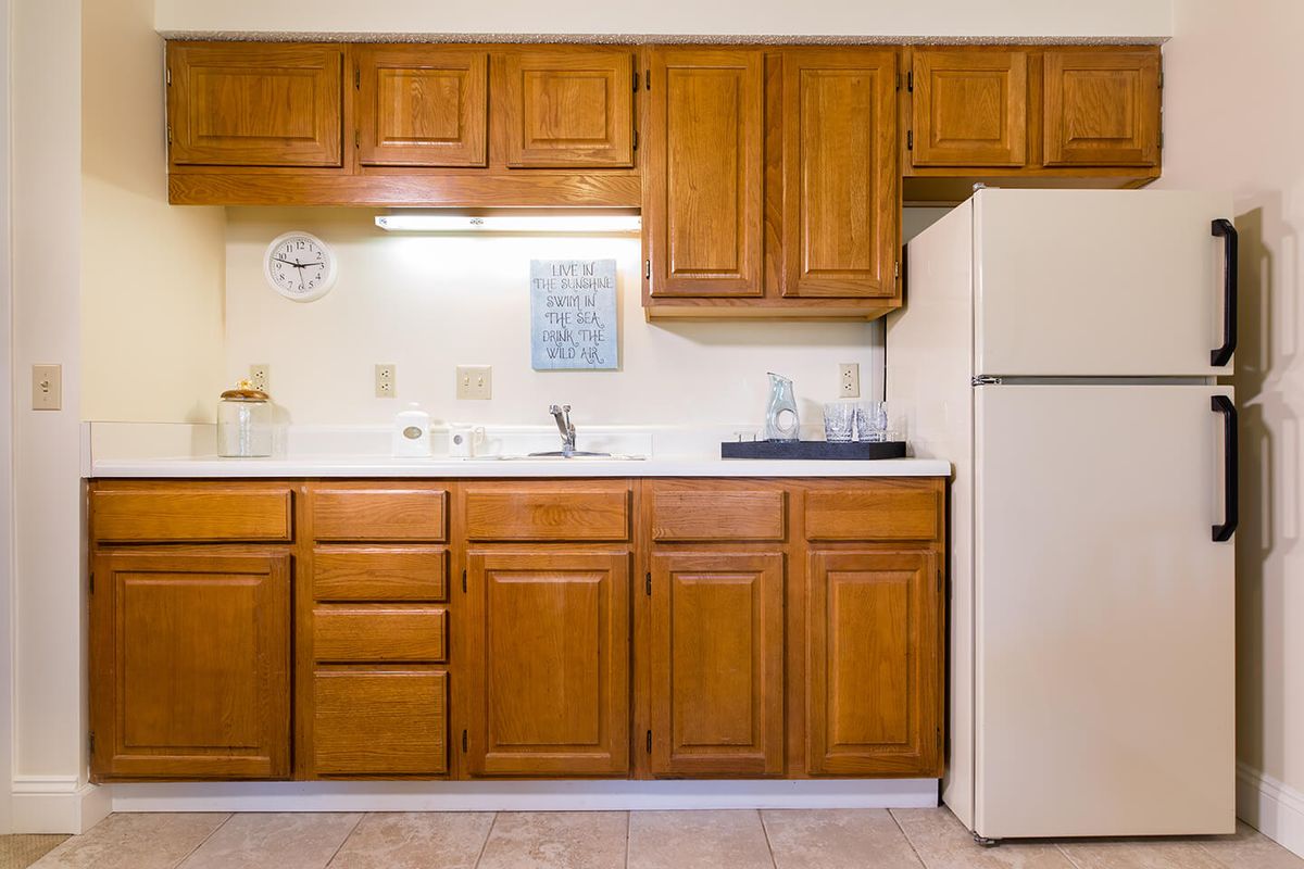 A kitchen with wooden cabinets, a fridge, and a sink.