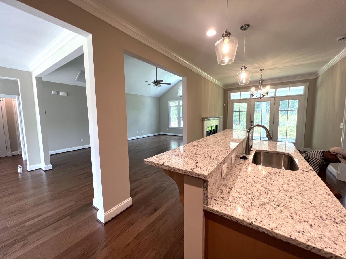 A modern open floor plan showcasing a kitchen with granite countertops and hardwood floors leading into a spacious living area.
