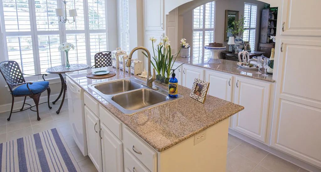 A modern kitchen with a granite countertop island, featuring dual sinks and elegant decor.
