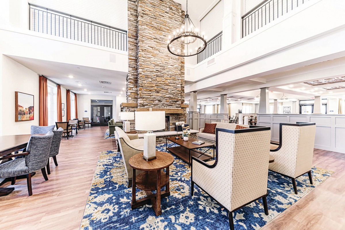 A modern lobby with a stone fireplace, elegant seating, and a large chandelier.