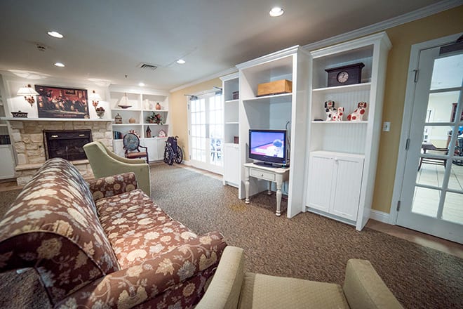 Cozy living room with floral sofa, built-in bookshelves, and a small television.