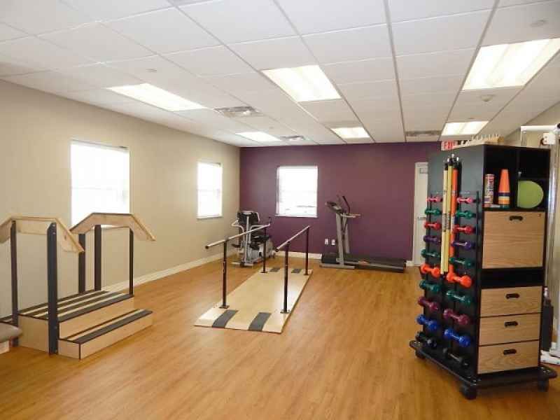 A well-equipped gym featuring exercise equipment and a colorful set of dumbbells.