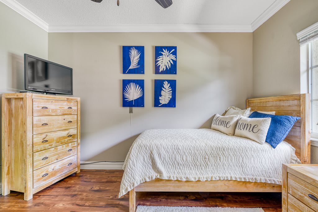 A cozy bedroom with wooden furniture and blue-themed artwork on the wall.