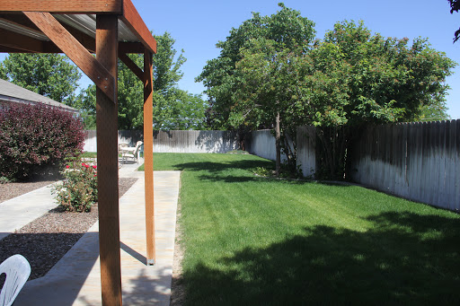 A spacious backyard with a well-maintained lawn and surrounding trees under a clear blue sky.