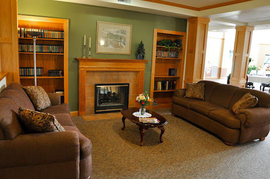 A cozy living room with a fireplace, sofas, bookshelves, and a coffee table.