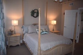 A cozy bedroom with a neatly made bed, flanked by two lamps on bedside tables.