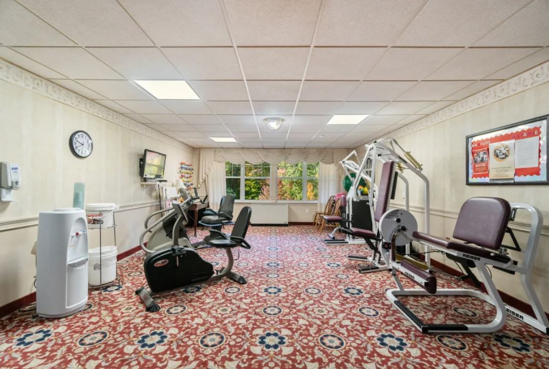 A small indoor gym with various exercise machines and a carpeted floor.