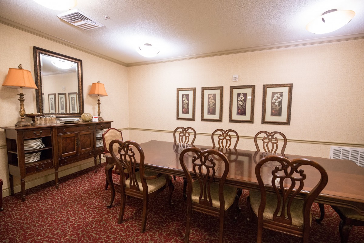 A classic dining room with a wooden table, chairs, and framed artwork on the walls.
