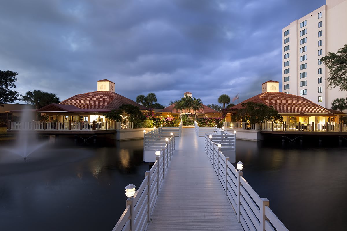 A scenic view of a bridge leading to buildings over water under a cloudy evening sky.