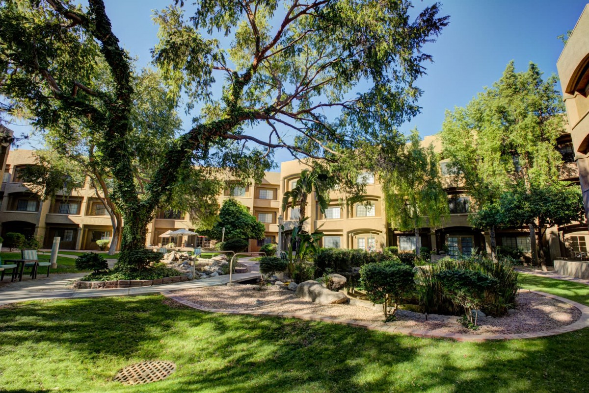 A sunny day view of a building surrounded by lush greenery and trees.