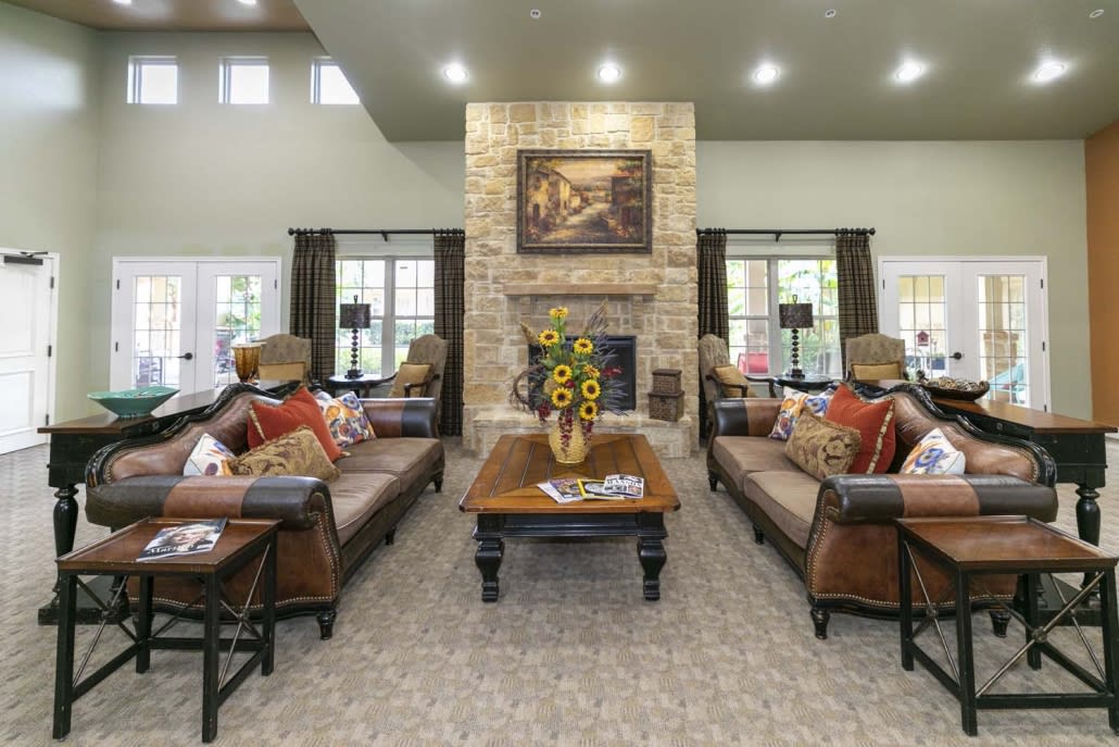 A cozy living room with a central fireplace, surrounded by sofas and a coffee table adorned with flowers.