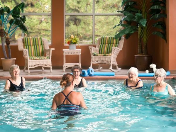 A group of people participating in a water aerobics class in an indoor swimming pool.