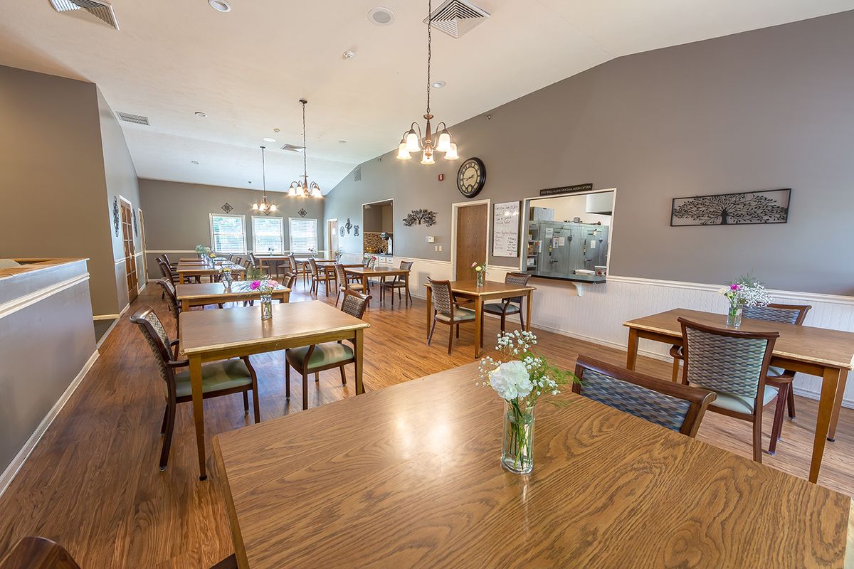 Spacious dining area with wooden tables and chairs, illuminated by elegant light fixtures.