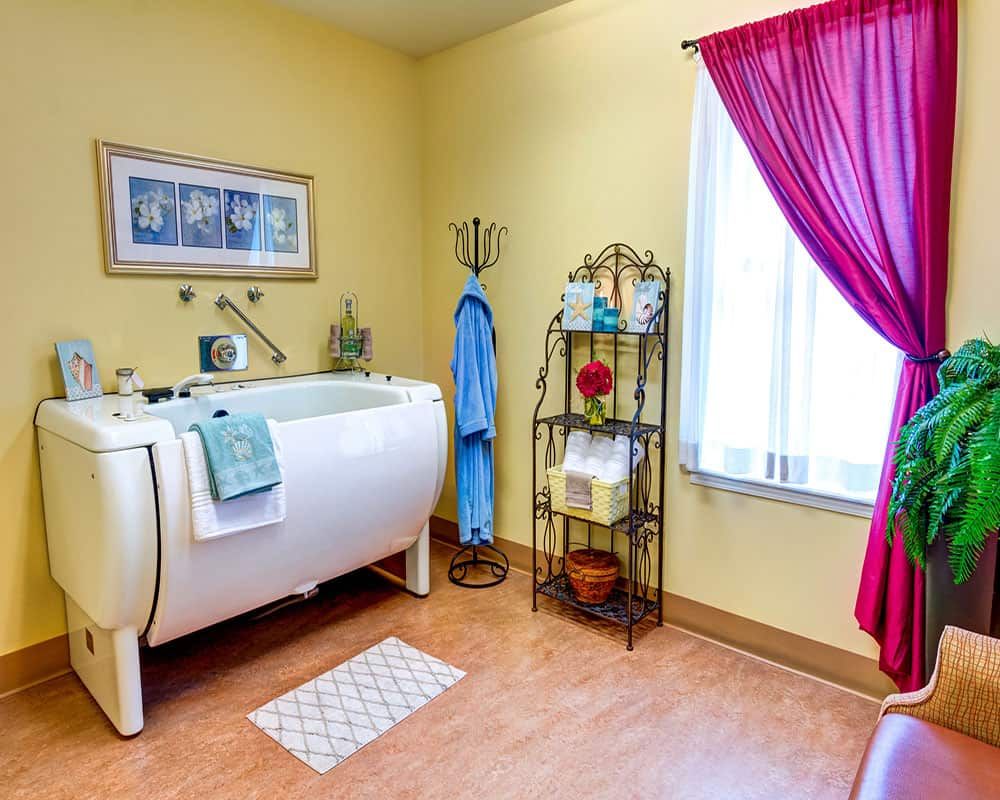 A cozy bathroom with a vintage bathtub, colorful towel rack, and bright curtains.