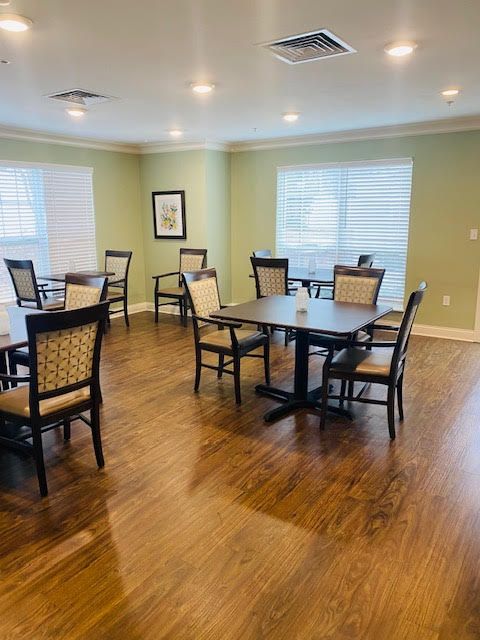 A well-lit dining area with multiple tables and chairs on a hardwood floor.