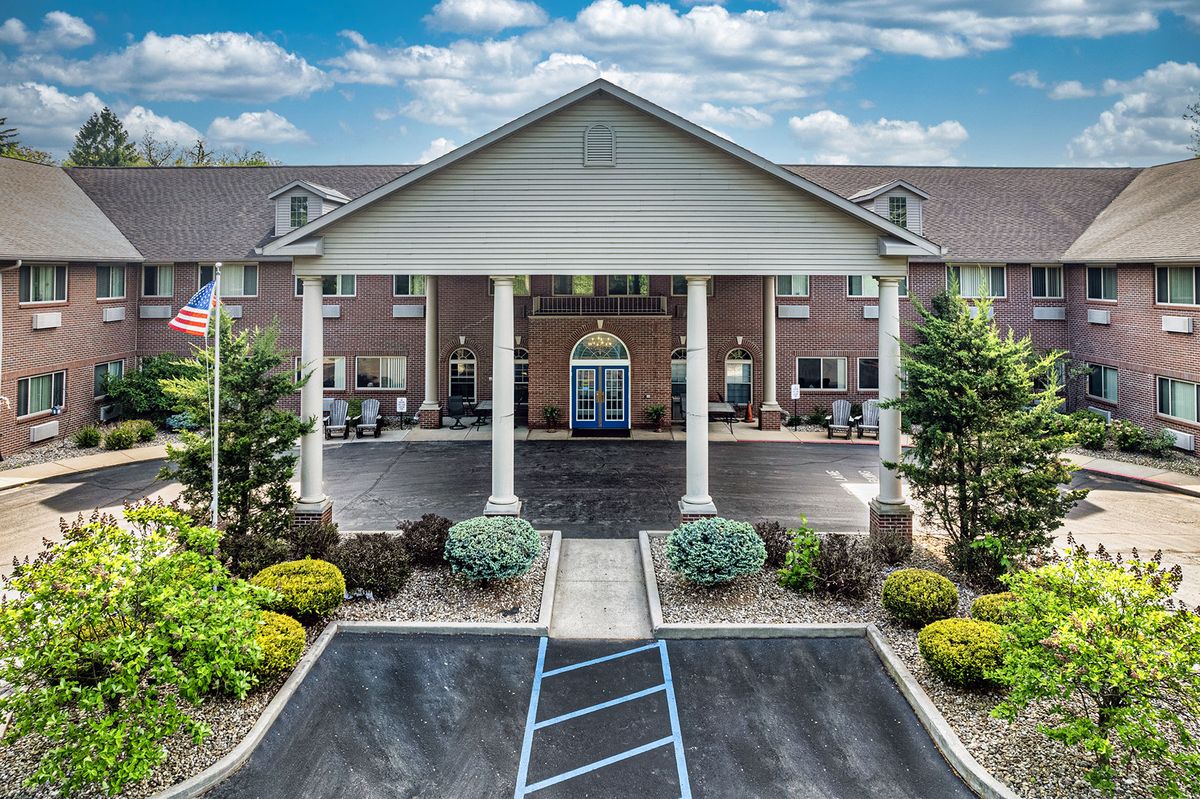 A well-maintained hotel entrance with a landscaped garden and clear sky.
