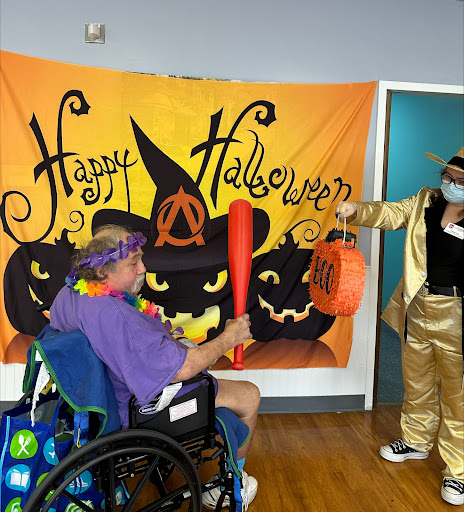 A festive Halloween celebration with decorations and costumes, featuring a participant in a wheelchair.