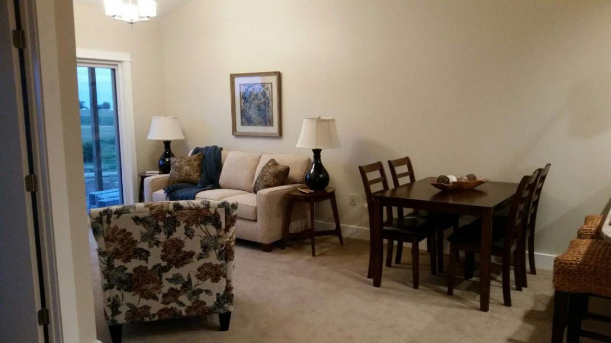 A cozy living room featuring a sofa, chairs, and a dining table illuminated by lamps.
