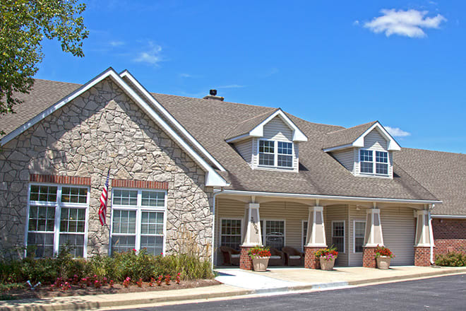 A residential building with stone facade and pitched roof under a clear blue sky.