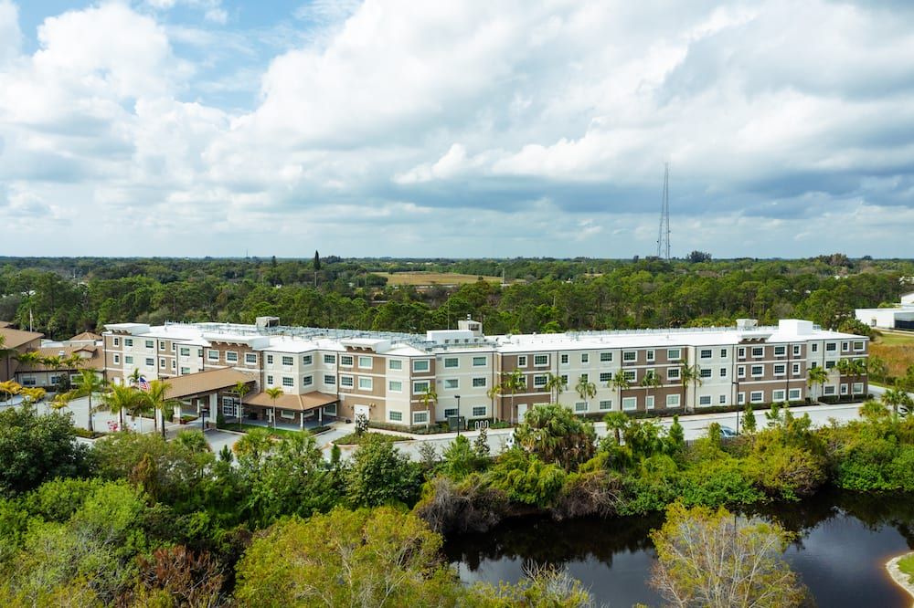 Aerial view of a modern building surrounded by lush greenery and a small body of water.