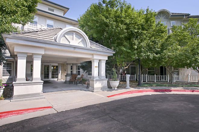 The entrance of a building surrounded by trees and a clear pathway.