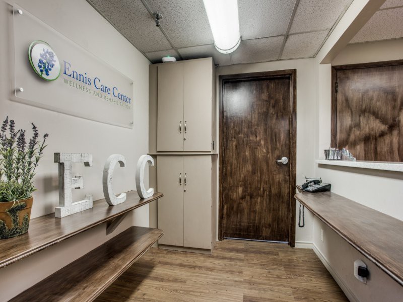 A medical clinic's waiting area with wooden flooring and a reception counter.