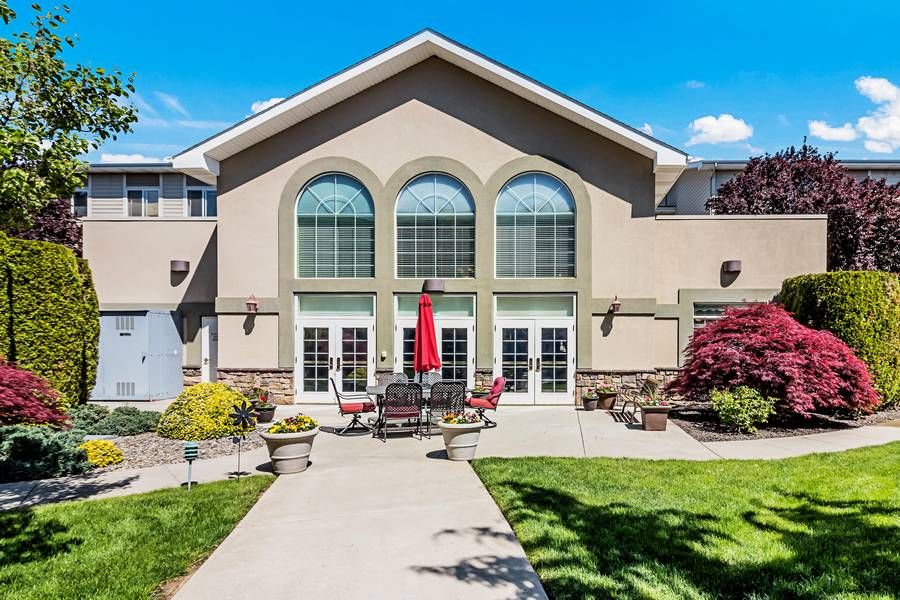 A modern building with arched windows and a patio area set against a clear blue sky.