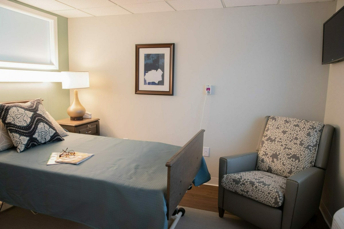 A hospital room with a bed, chair, and lamp.