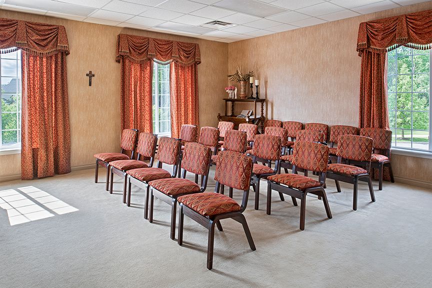 Small chapel with arranged seating and a decorative window.