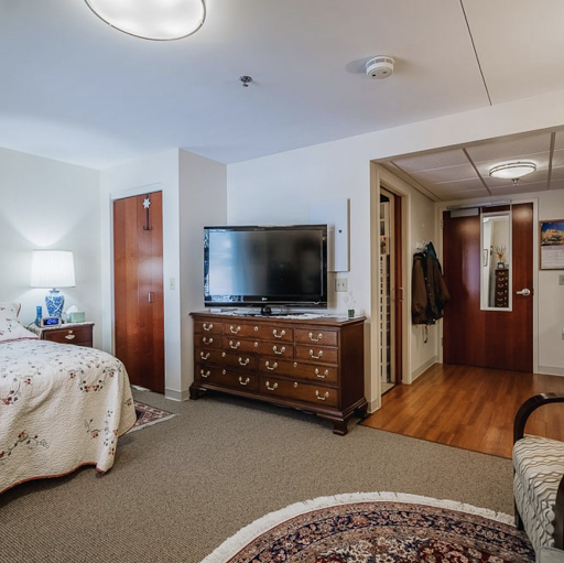 A cozy and well-furnished bedroom featuring a television, decorative carpet, and warm lighting.