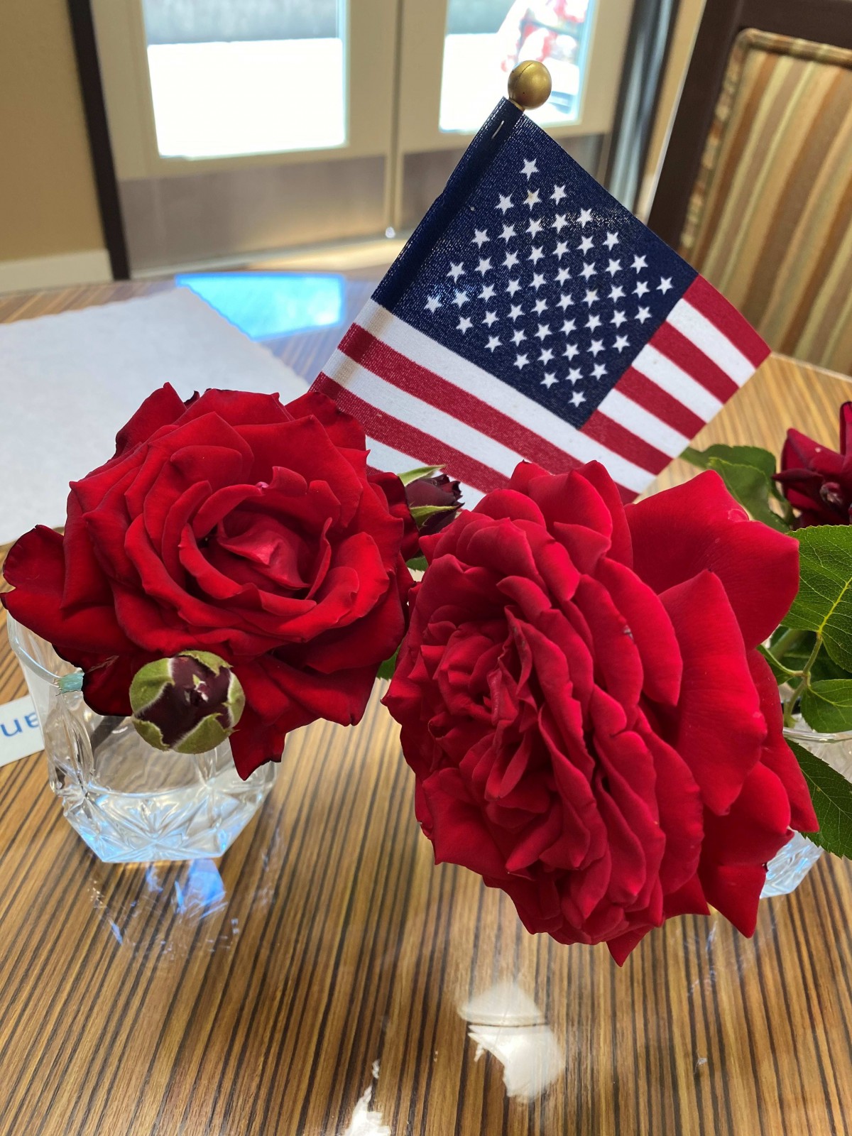 A beautiful arrangement of red roses accented with a small American flag.